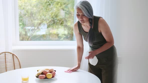 Asian concentrated woman wiping the dining table
