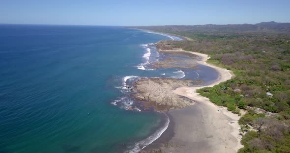 Aerial drone view of the beach, rocks and tide pools in Playa Palada, Guiones, Nosara, Costa Rica