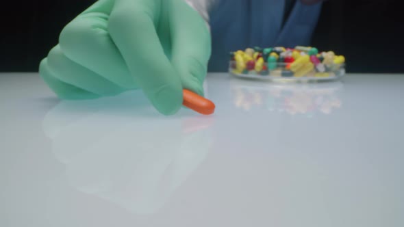 Lab Worker Moving Orange Pill to Camera