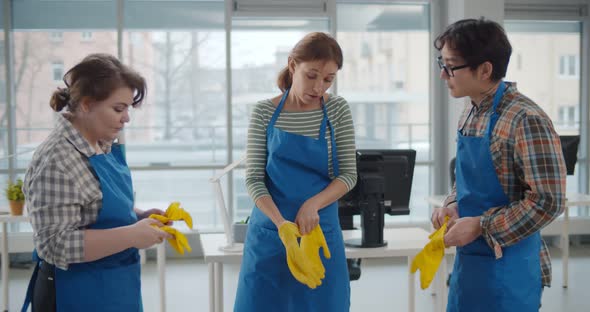 Diverse Team of Janitor Putting on Rubber Gloves Preparing To Clean Office