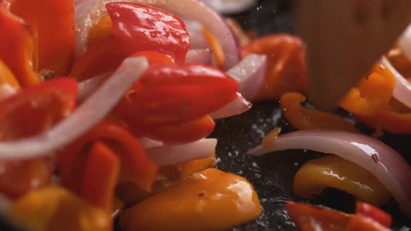 Stir frying onion and orange and red bell pepper. Slow Motion.