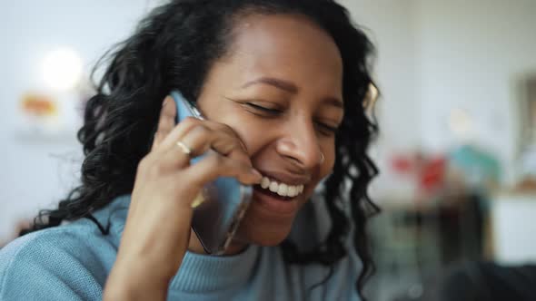 Smiling African woman wearing blue sweater talking on phone