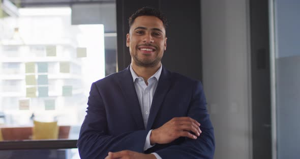 Portrait of mixed race businessman with arms crossed smiling looking at camera