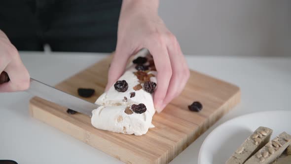 Woman hands cut white sweet pakhlava with raisins into slices on board