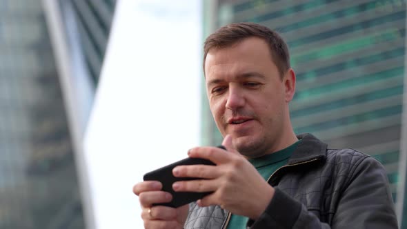 Excited Mature Man Captivated By Online Gaming Walking on Street at City