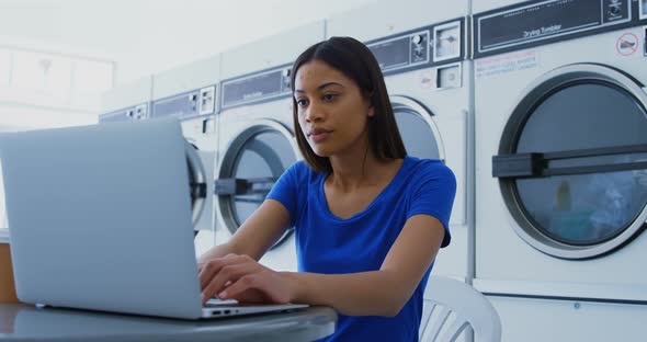 Woman using laptop at laundromat 4k