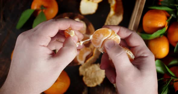 Men Hands Divide the Tangerine Into Slices