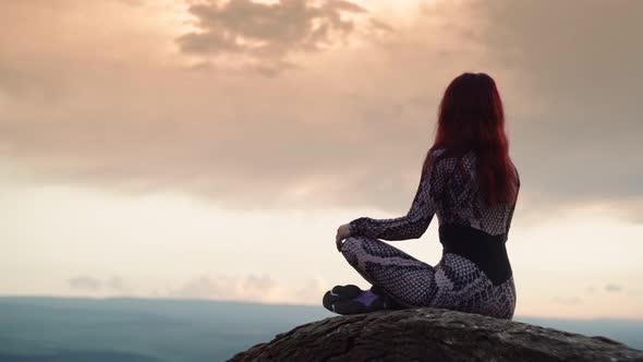 Slender Girl Sits in Lotus Position on the Top Mountain During Beautiful Sunset