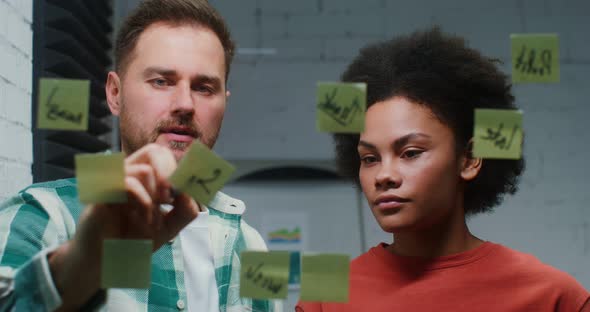 A Young Man and Woman are Planning in the Office Drawing on a Glass Board