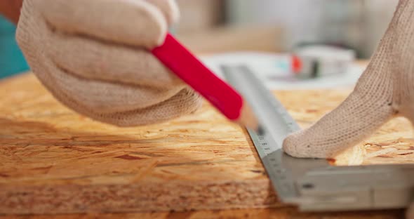 Closeup of a Hardworking Professional Carpenter Holding a Angular Ruler and Pencil While Measuring a