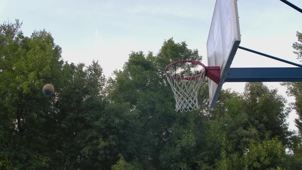 Young Man Trains Jumping with Ball To Hit Ring. Basketball Player Play Outdoors. Sport Motivation