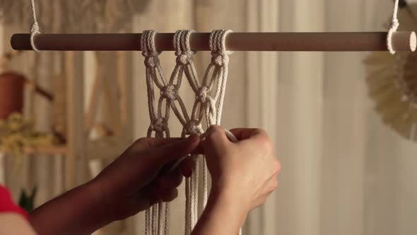 A Woman Craftsman Weaves Macrame From Light Cotton Threads in Her Home Workshop