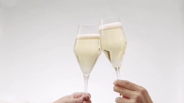 Two Glasses of Champagne Approach and Collide in Slow Motion on White Background