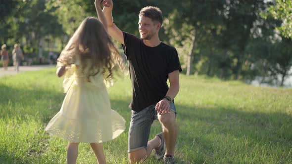 Carefree Playful Girl Spinning in Sunshine Holding Man Hand