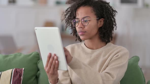 Portrait of African Woman Celebrating On Tablet on Sofa