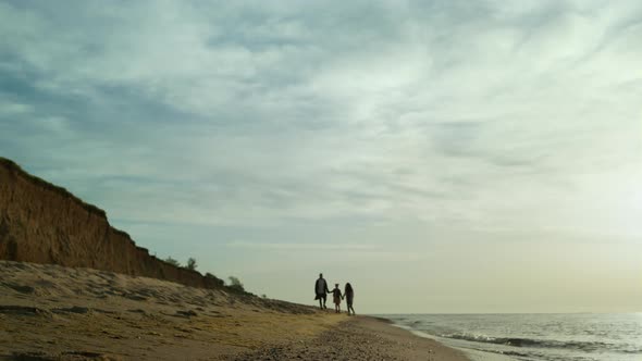 Family Silhouettes Walking Sand Shore By Seascape Beach