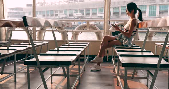 Woman visit Hong Kong and taking ferry with her cellphone under sunset