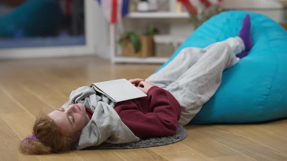 Wide Shot of Exhausted Caucasian Woman Sleeping on the Floor with Feet Up