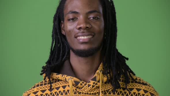 Young Handsome African Man with Dreadlocks Against Green Background