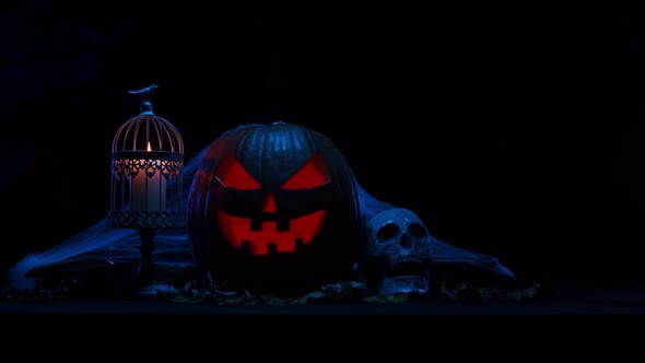 Scary laughing pumpkin and an old skull over the frightening gothic background.