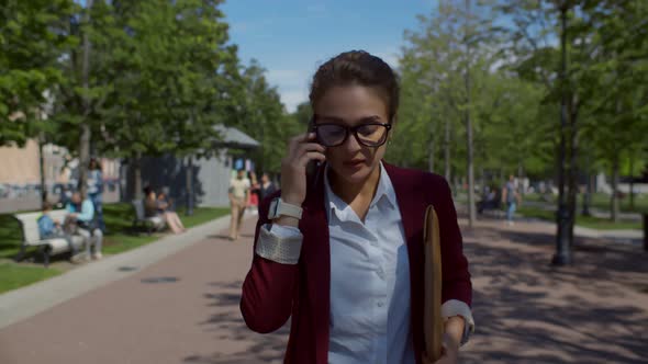 Young Woman in Office Suit Going Down Urban Alley and Calling on Cellphone