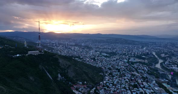 Aerial view of center of Tbilisi under Mtatsminda mountain at sunset. Georgia 2022 summer