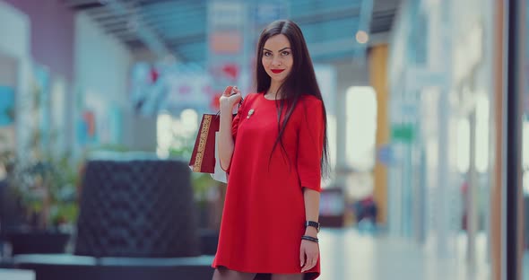 Portrait of an Attractive Woman in a Shopping Center with Paper Bags in Her Hands