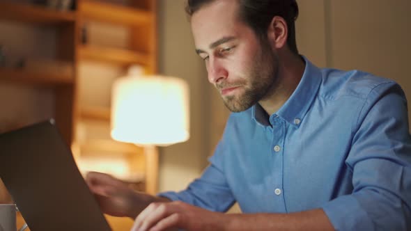 Confident man texting by laptop