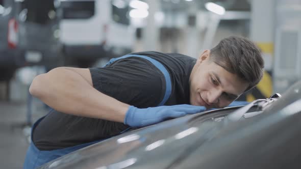 Young Caucasian Brunette Service Man Stroking Car Hood Smiling