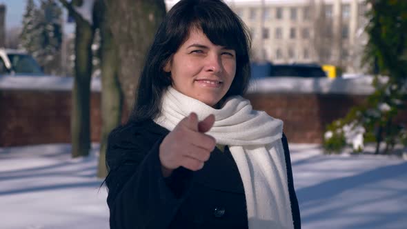 Beautiful Smiling Girl Makes Thumb Up Gesture. Snow Covered Park. Winter City