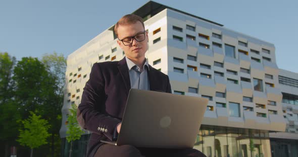 A Businessman Is Completing Work on a Laptop