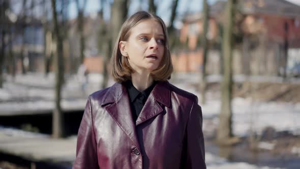 Front View Portrait of Confident Relaxed Caucasian Woman in Elegant Purple Coat Walking in Sunshine