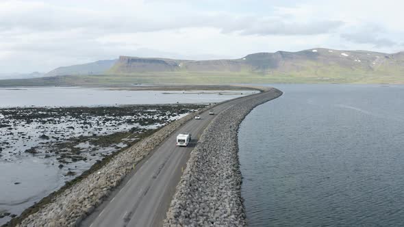 Aerial View Of The Vehicles Traveling On The Road Amidst The Waterscape In Westfjords, Iceland.