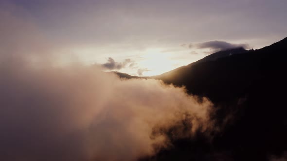 The Drone Flies Through the Clouds at the Mountain Peaks