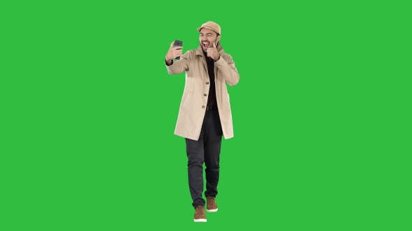 Cheerful man in coat taking photo making selfie on a Green