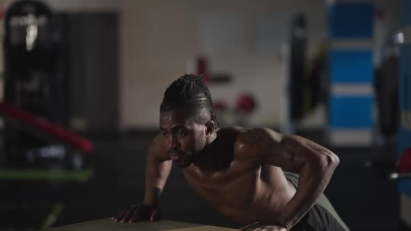 Motivated Tattooed African American Man Doing Pushups on Gym Cube Indoors