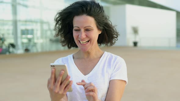 Smiling Mature Woman Using Smartphone on Street