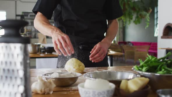 Caucasian male chef kneading dough on a kitchen table