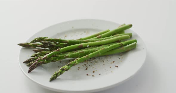 Video of fresh asparagus stalks on white plate over white background