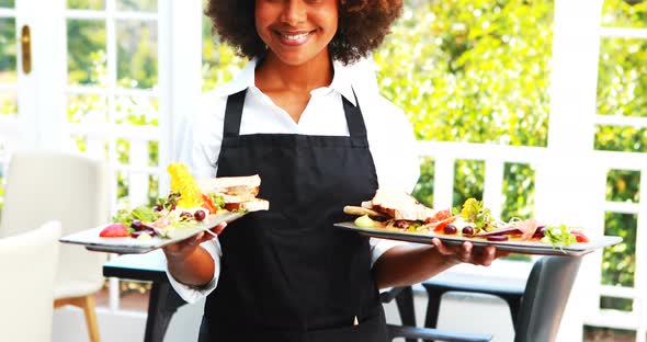 Portrait of smiling waitress holding food tray