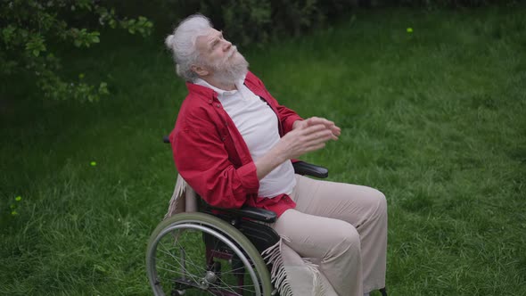 High Angle View of Disabled Bearded Senior Man Holding Hands Together Closing Eyes Praying