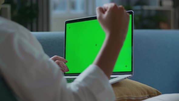 Close Up Of A Man Celebrating While Lying On Sofa And Using Green Screen Laptop In The Living Room