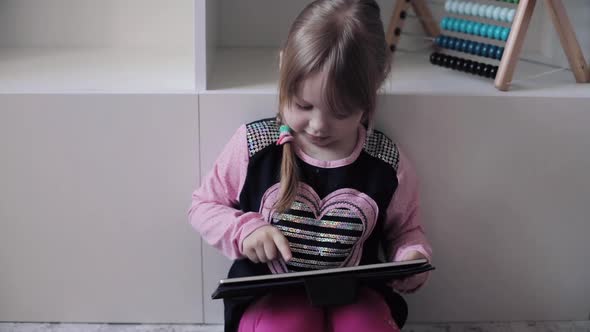 Funny Child Sitting on Floor and Using Electronic Devices