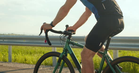 A Sportsman on a Bicycle is Riding Along the Highway