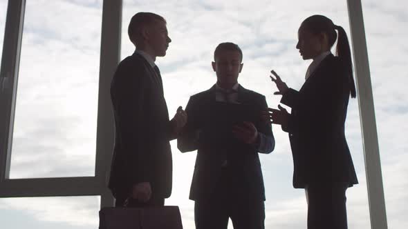 Business Executives Discussing Work before Panoramic Window