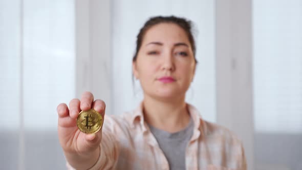 Blurred Young Brunette Woman Holding Golden Bitcoin in Her Hand