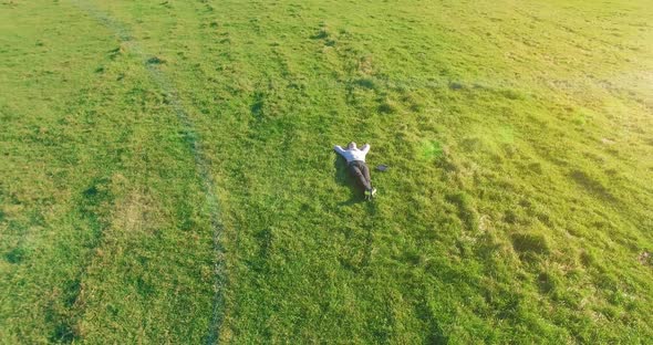 Low Orbital Flight Around Man on Green Grass with Notebook Pad at Yellow Rural Field.