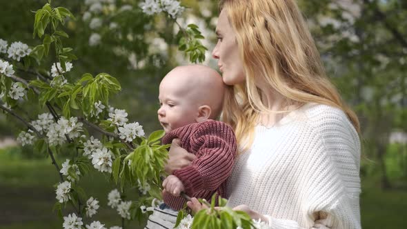 mom with a baby in her arms in a blooming garden