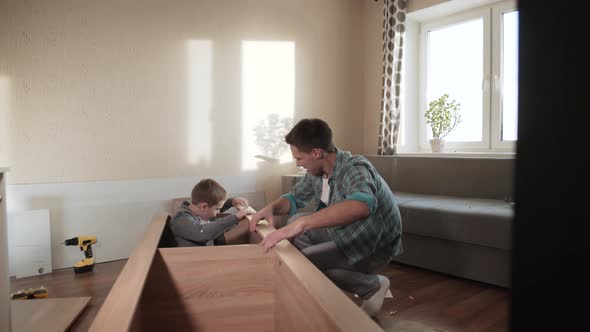 Happy Father and Son Install Detail on Dowels During Assembly of New Wardrobe