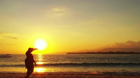 Young smiling lady in the sun at the beach on clean white sand and blue background 4K